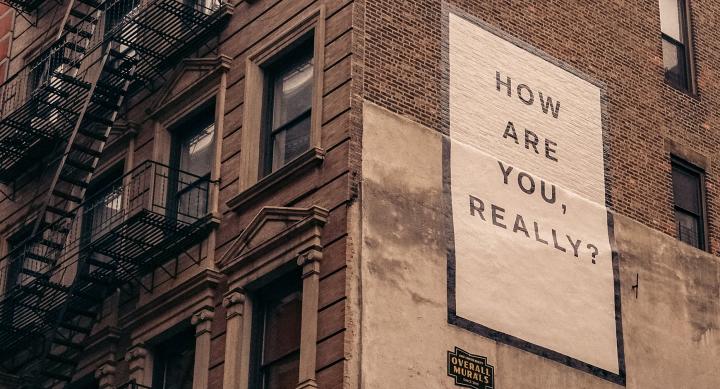 Sign on the side of a building that says How are you, really?