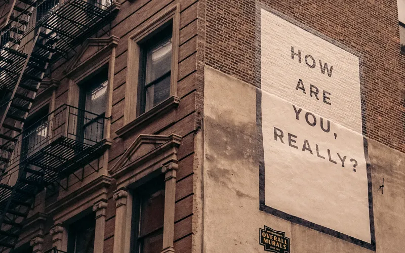 Sign on the side of a building that says How are you, really?
