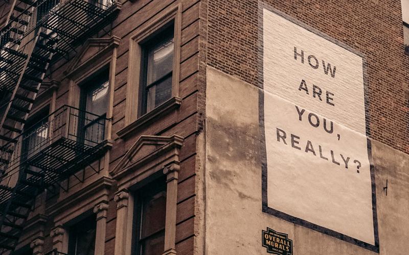 Sign on the side of a building that says How are you, really?