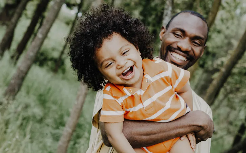 African American father and kid laughting and playing together